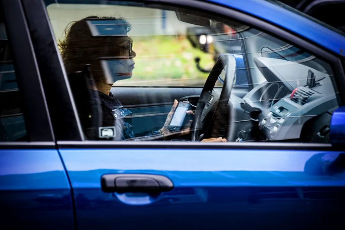 dame in auto die een smartphone in haar hand vasthoudt