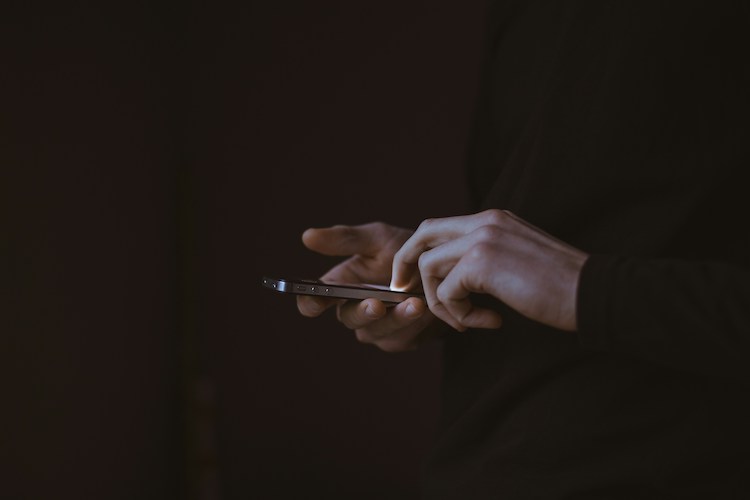 Twee handen houden een smartphone vast. Zwarte achtergrond