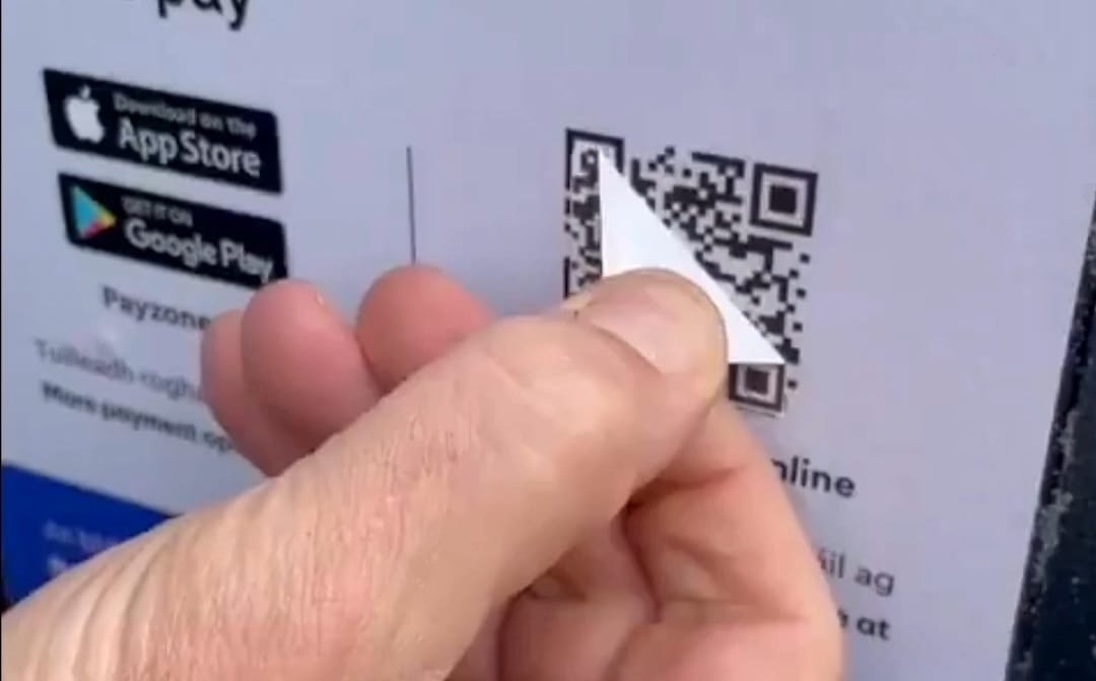 Iemand die over een QR code stiekem een andere QR code plakt