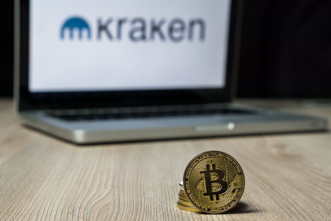 Laptop met op scherm het logo van Kraken en op de voorgrond een BITCOIN muntje
