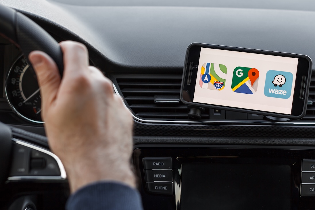 Smartphone in auto met op scherm drie icoontjes van navigatiesystemen