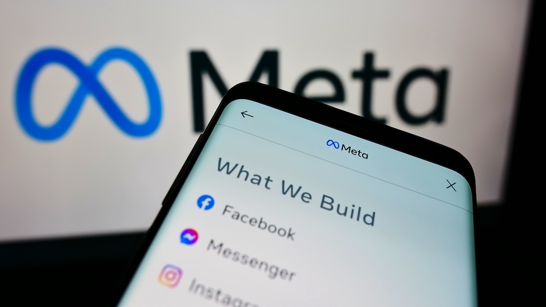 smartphone met icoontjes van Instagram, Messager en Facebook. Op achtergrond logo van META