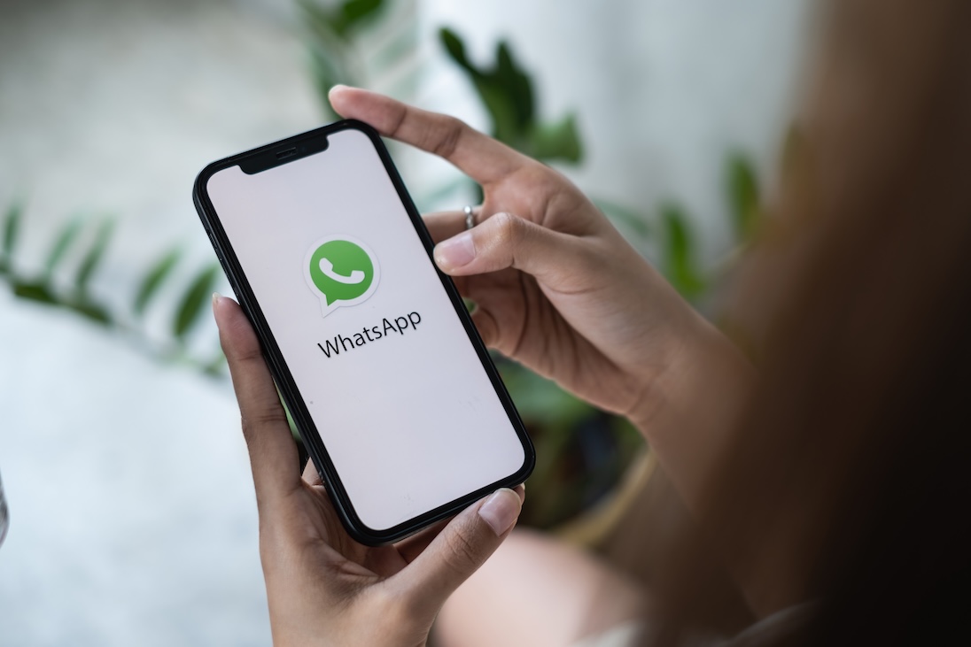 Twee handen houden een smartphone vast met daarop startscherm van whatsapp