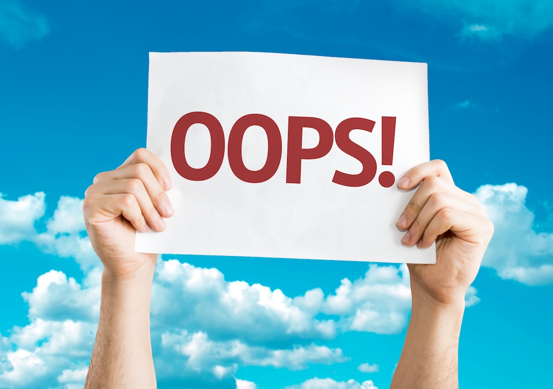 Twee handen houden een bord omhoog met daarop geschreven OOPS