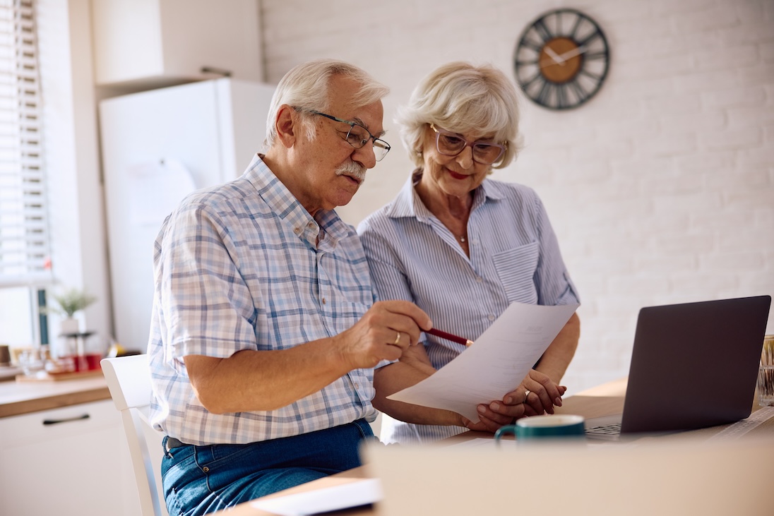 dame en heer kijken naar een formulier en een opengeklapte laptop