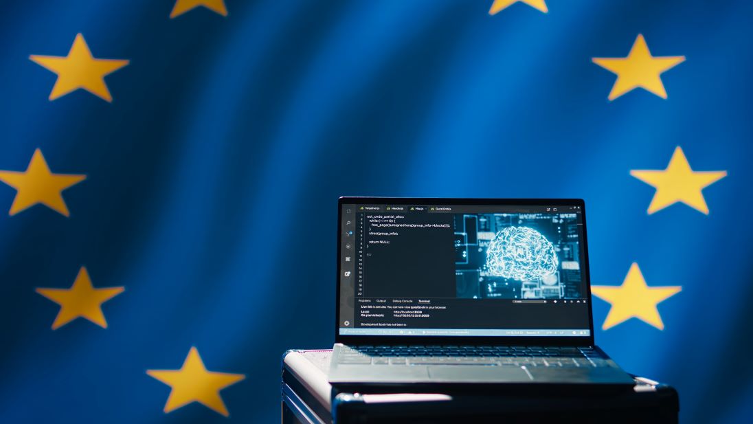 geopende laptop met op de achtergrond de vlag van Europese Unie