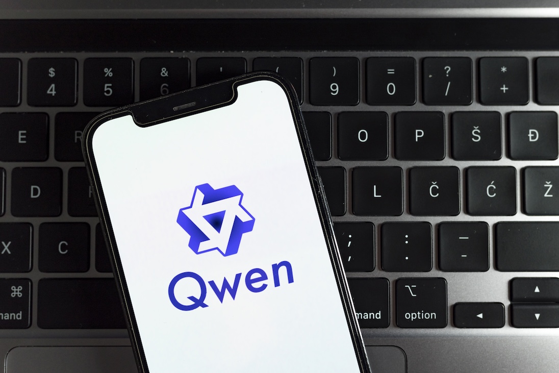 logo van Qwen op smartphone met daarachter een toetsenbord