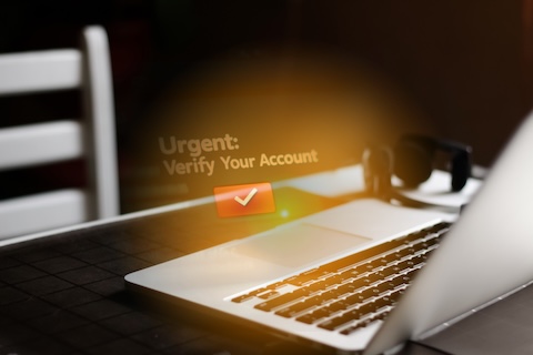 Urgent fake account verification notification popping up on a laptop, illustrating a common phishing scam targeting the user's inbox.