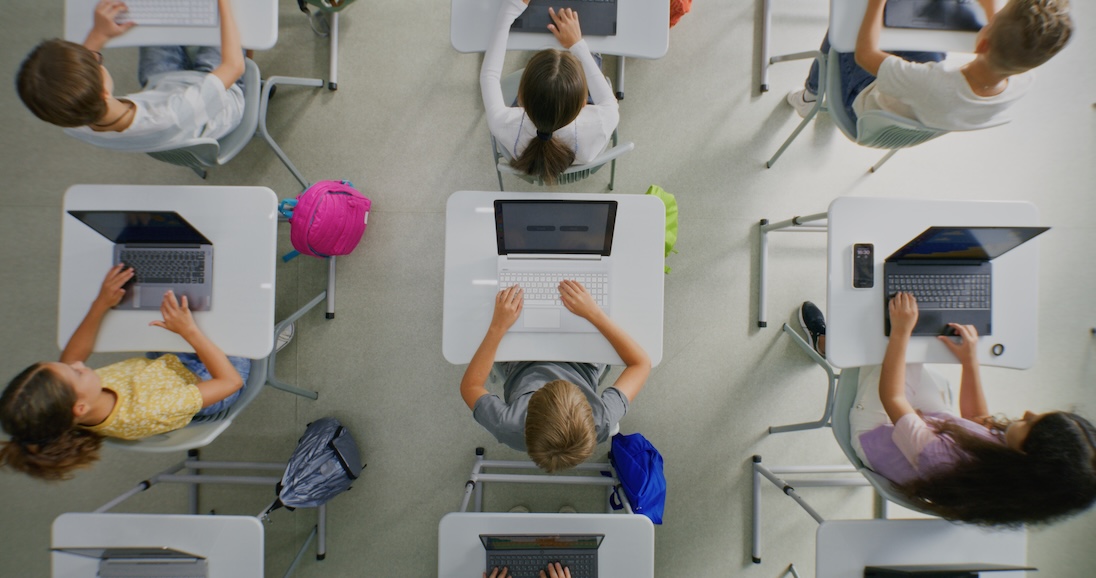 Schoolklas van boven gezien. Leerlingen met laptops op hun bureaus