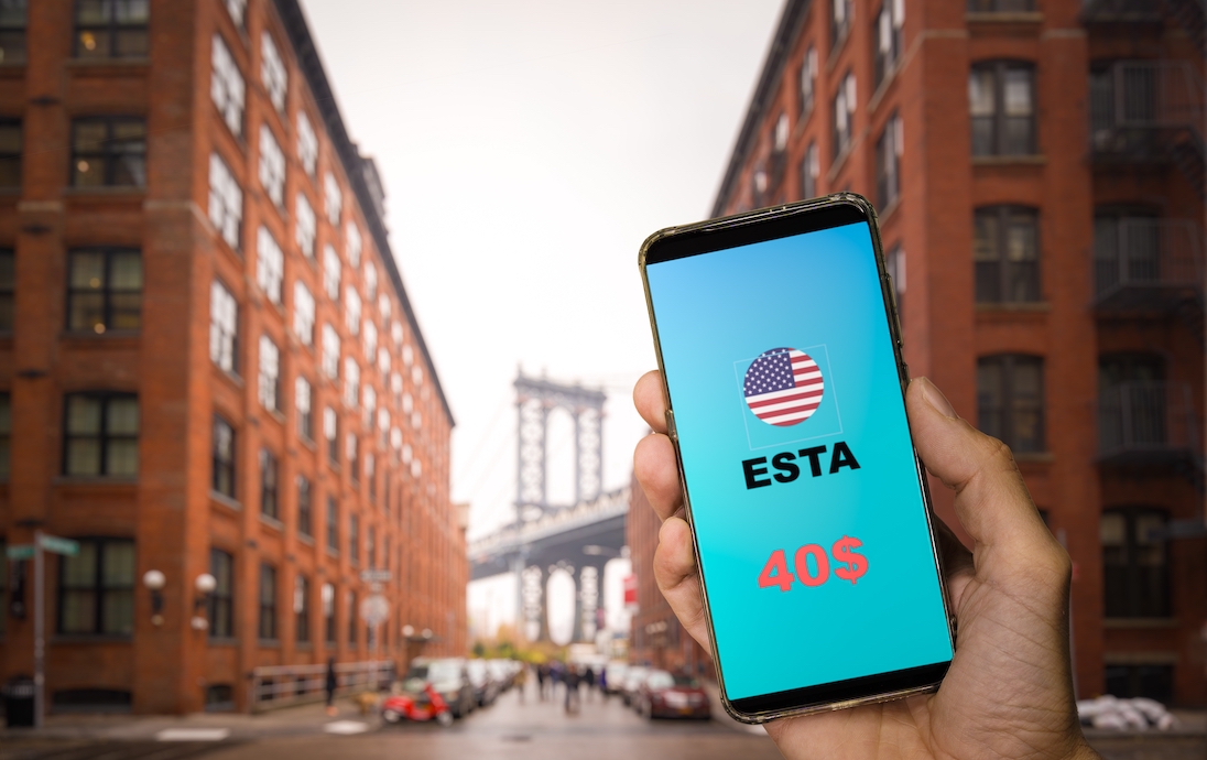 ESTA op smartphone, op achtergrond Brooklyn Bridge in New York City