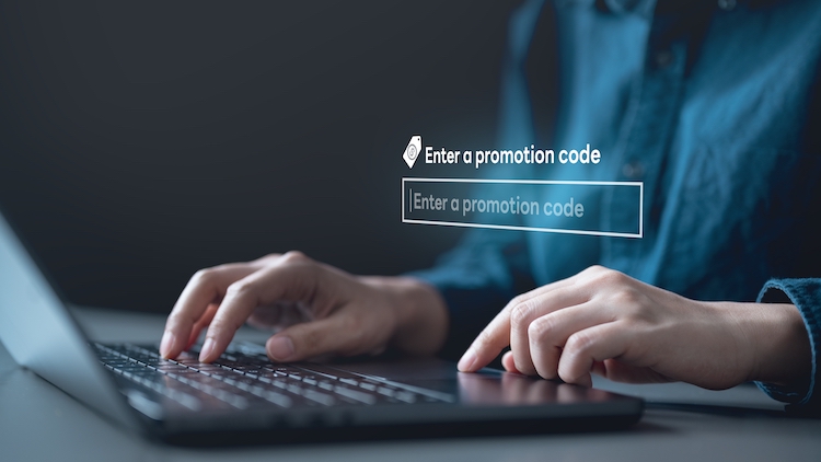 Twee handen die op een laptop een promotiecode intoetsen