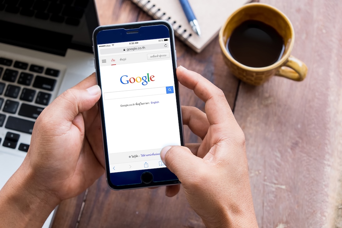 Google op smartphone en een kop koffie