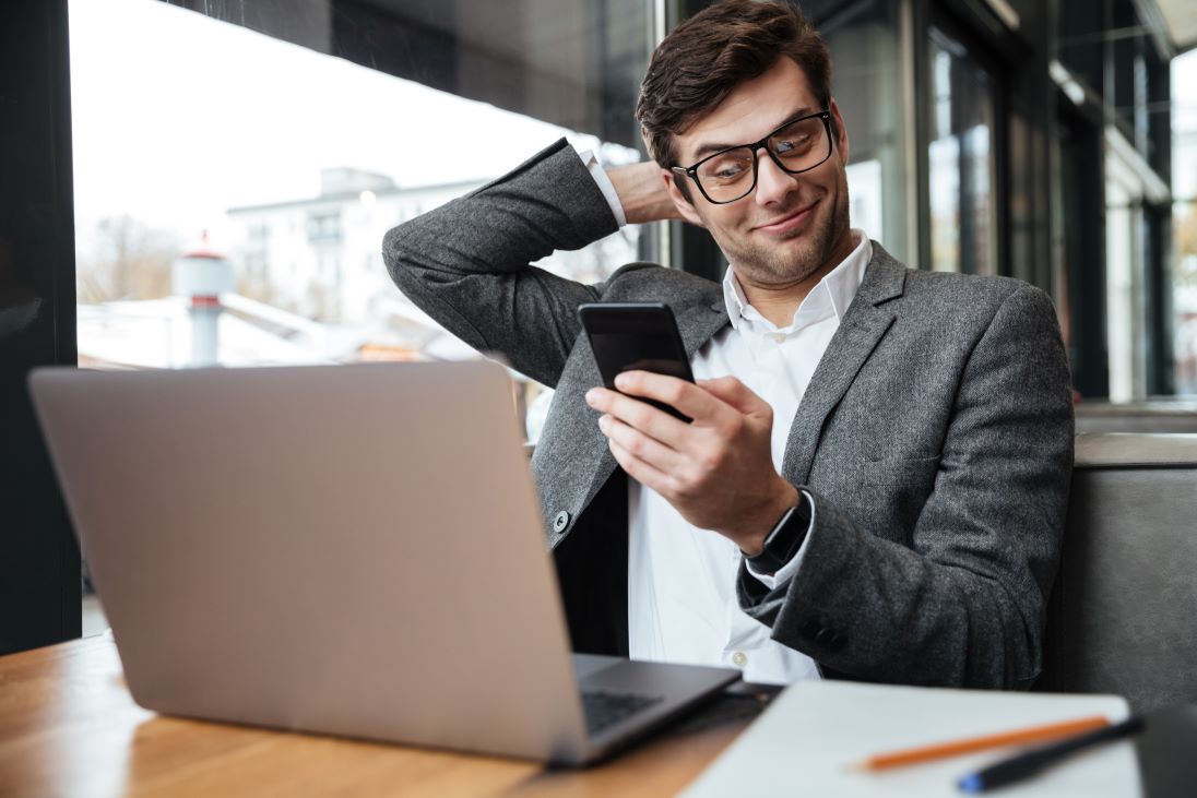 Man met smartphone en laptop